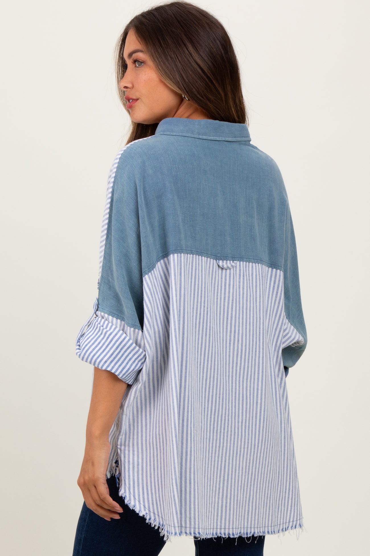 woman wearing a striped blue and white maternity top with a denim-like back and rolled sleeves