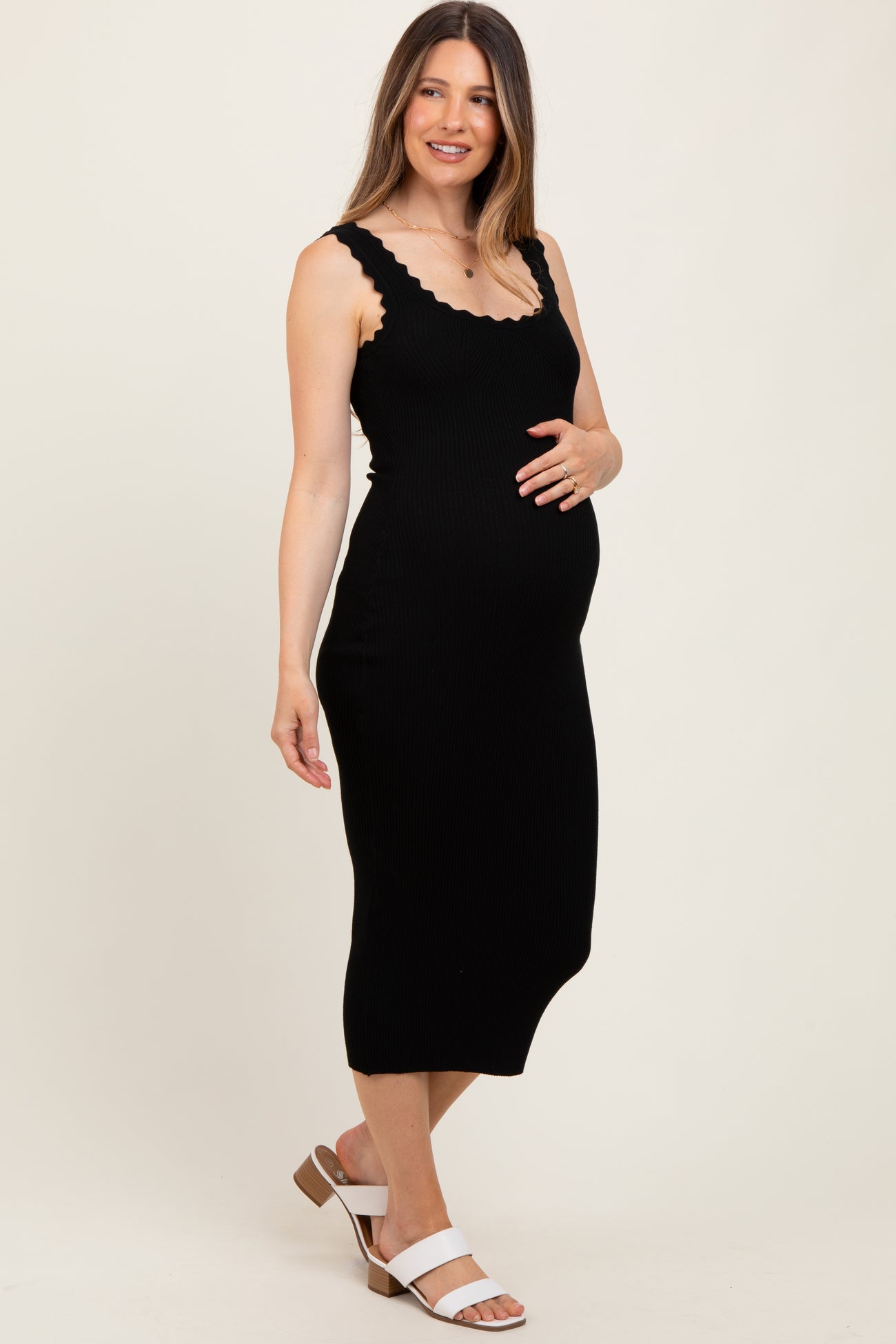 woman wearing a black ribbed maternity dress with scalloped neckline and baby bump visible