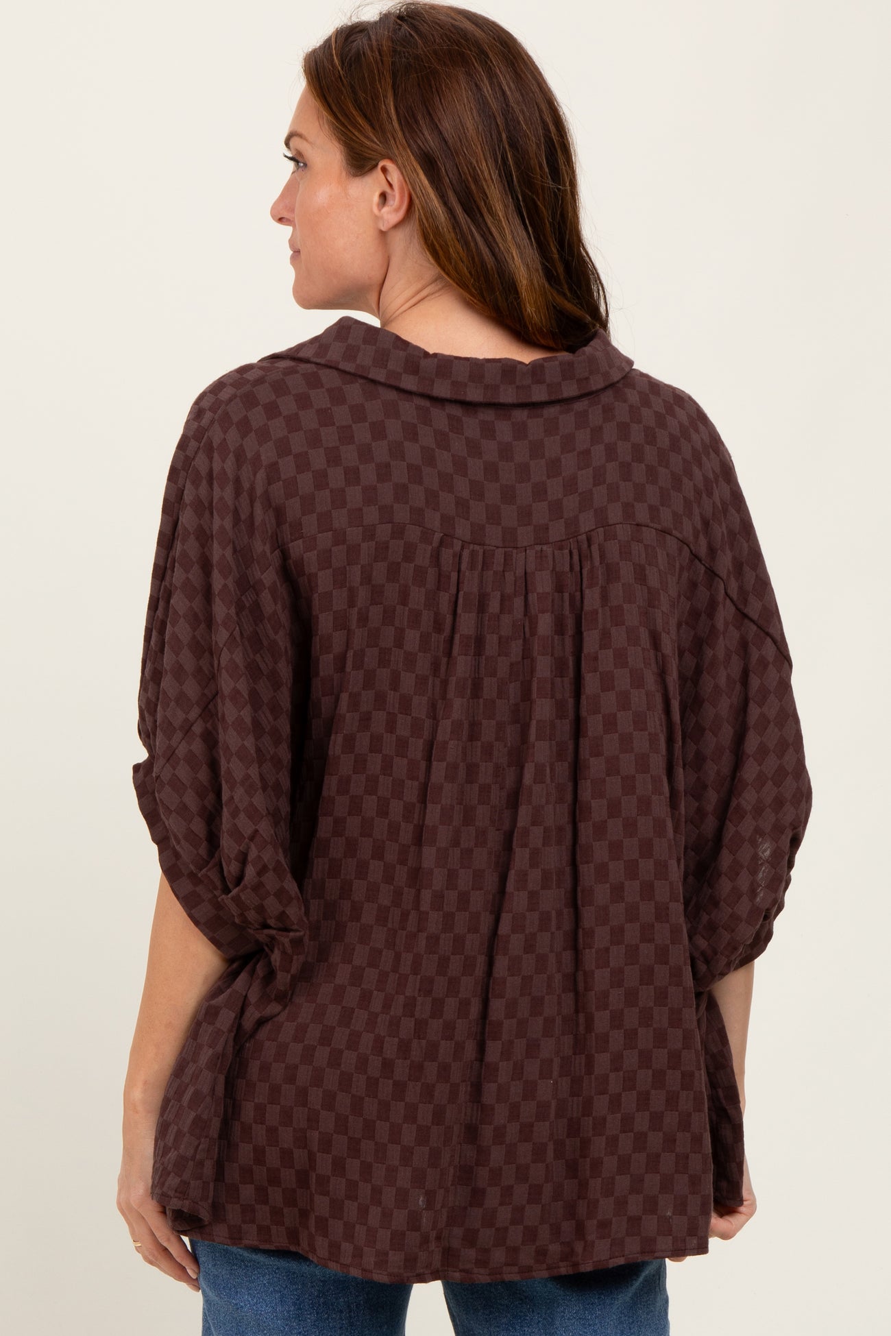woman wearing a burgundy checkered top with a relaxed fit and short sleeves, viewed from the back