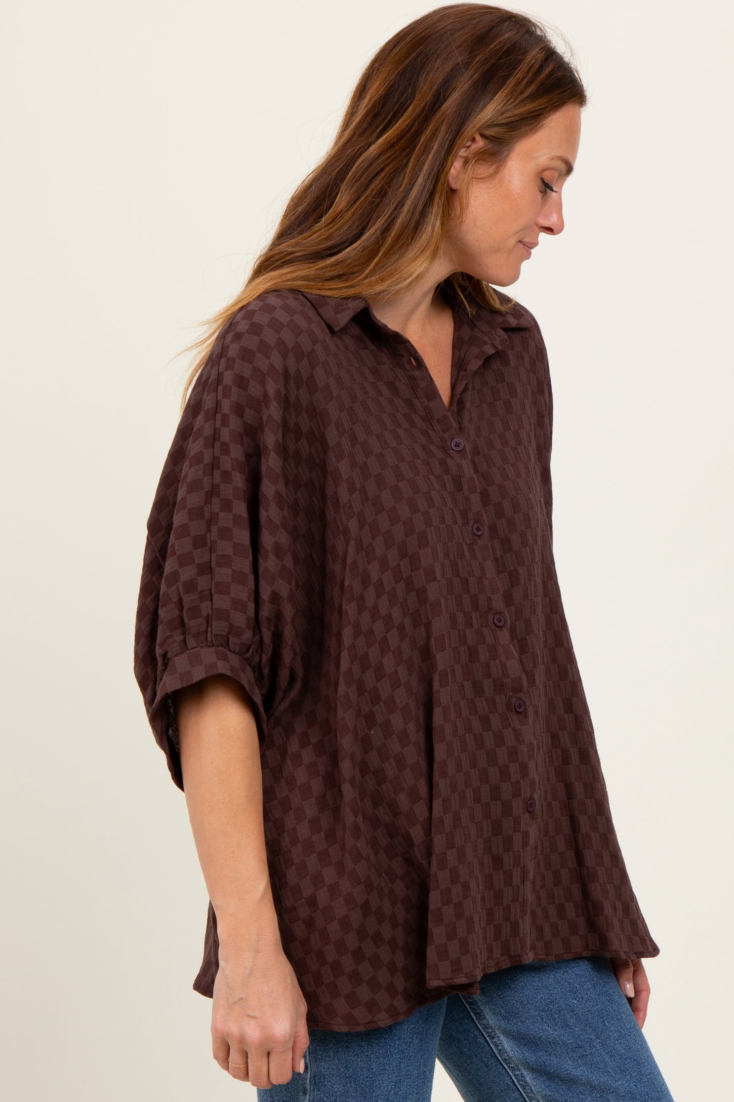 woman wearing a brown checkered button-up shirt with a relaxed fit and rolled-up sleeves