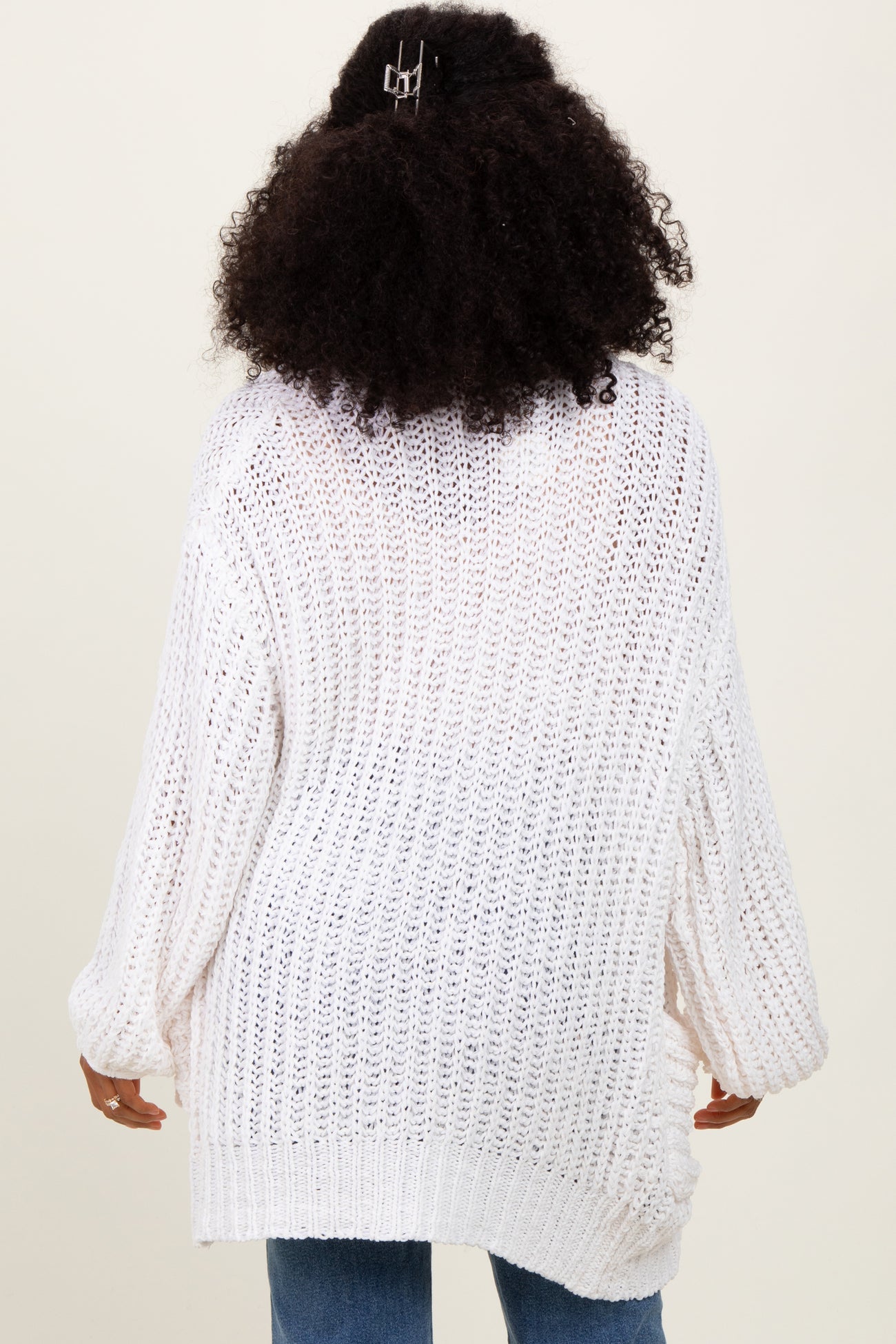 woman wearing a white oversized knit sweater with wide sleeves, shown from the back
