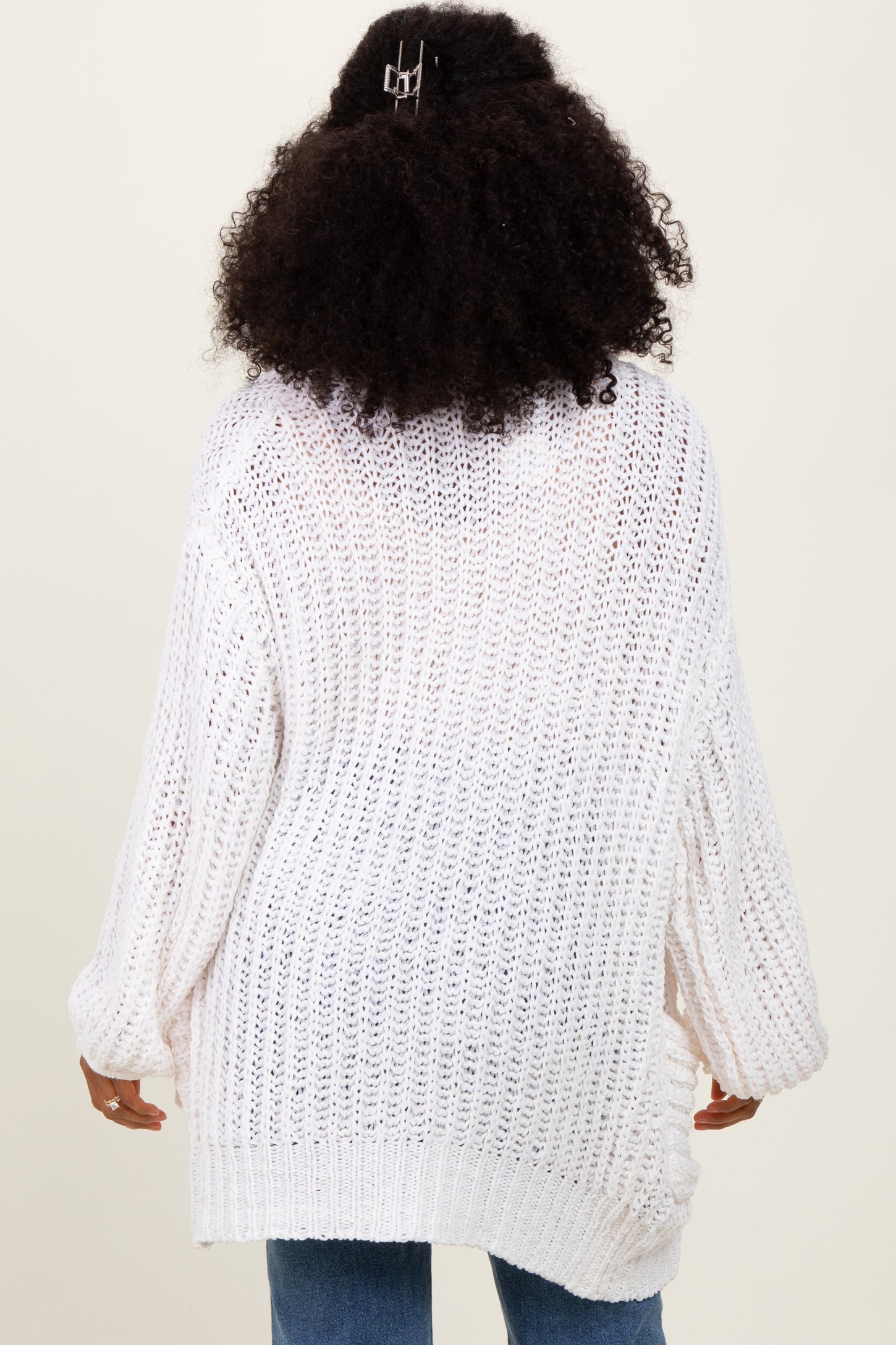 woman wearing a white oversized knit sweater with wide sleeves, shown from the back