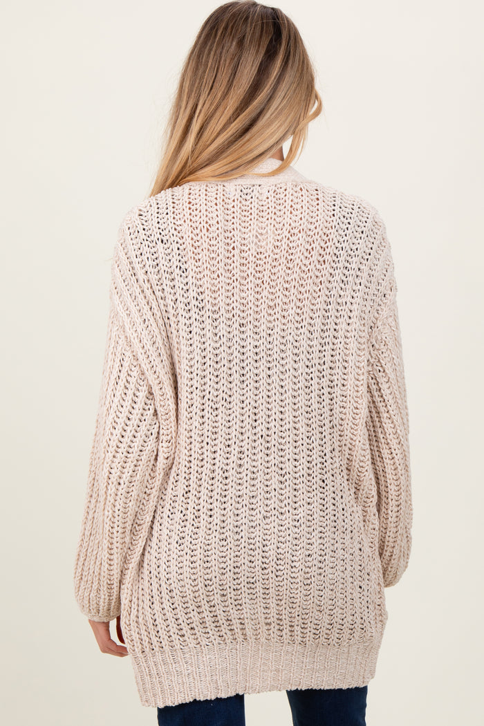 woman wearing a light beige loose knit maternity sweater viewed from the back