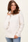 woman wearing a cozy cream ribbed sweater with a cowl neck and long sleeves, smiling and posing with one hand on her hip