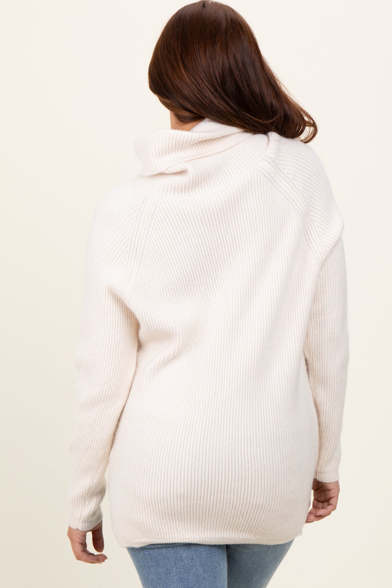 woman wearing a light pink oversized ribbed sweater with a cowl neck and long sleeves
