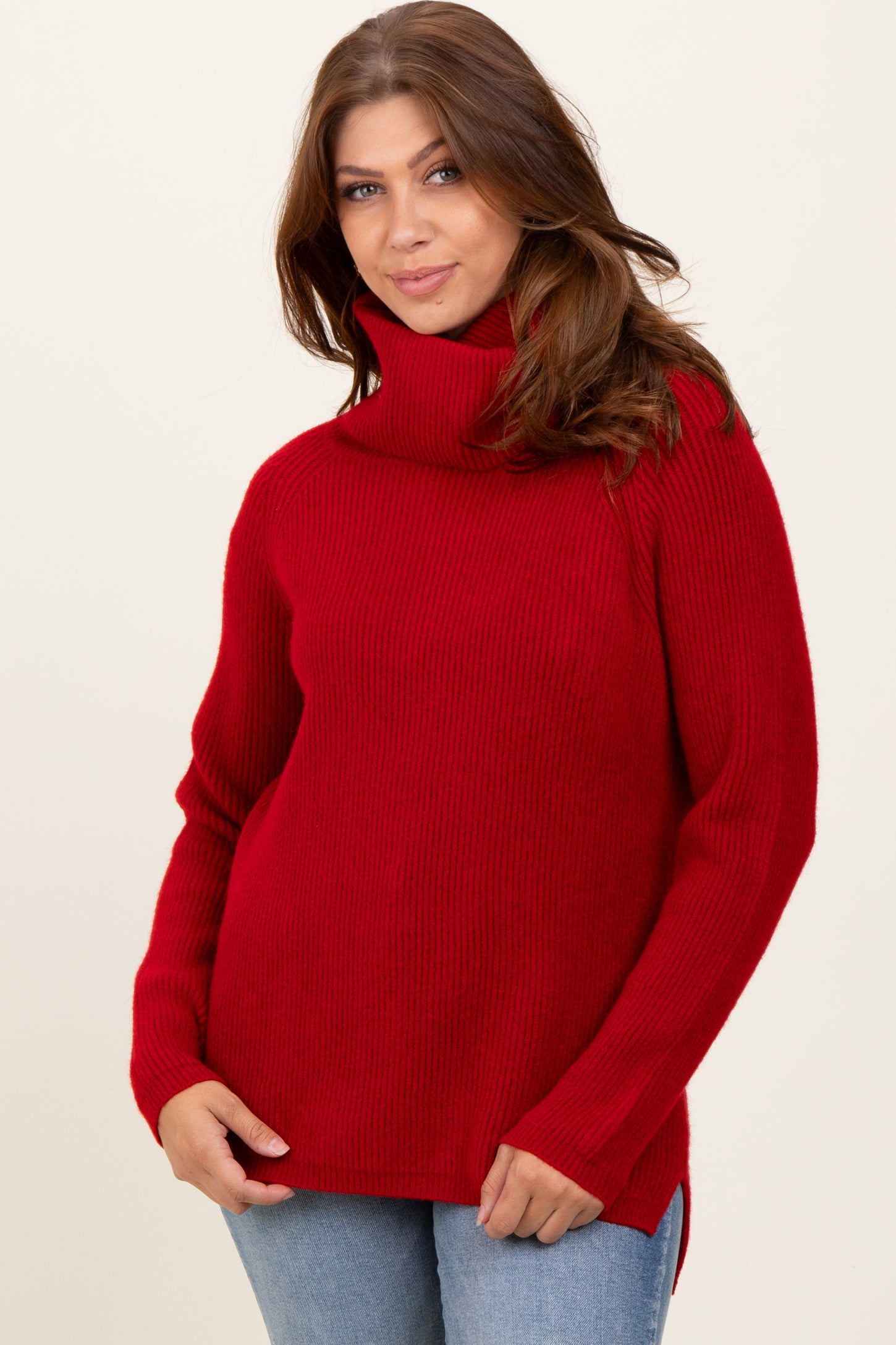 woman wearing a red turtleneck sweater with ribbed texture and side slits, styled with blue jeans