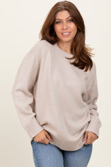 woman wearing a beige oversized sweater with ribbed cuffs and hem, paired with light blue jeans
