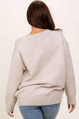 woman wearing a beige oversized sweater with a ribbed hem and back details, styled with blue jeans