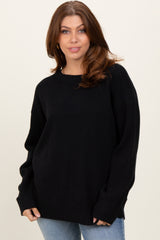woman wearing an oversized black sweater with a crew neck and long sleeves, styled with light blue jeans