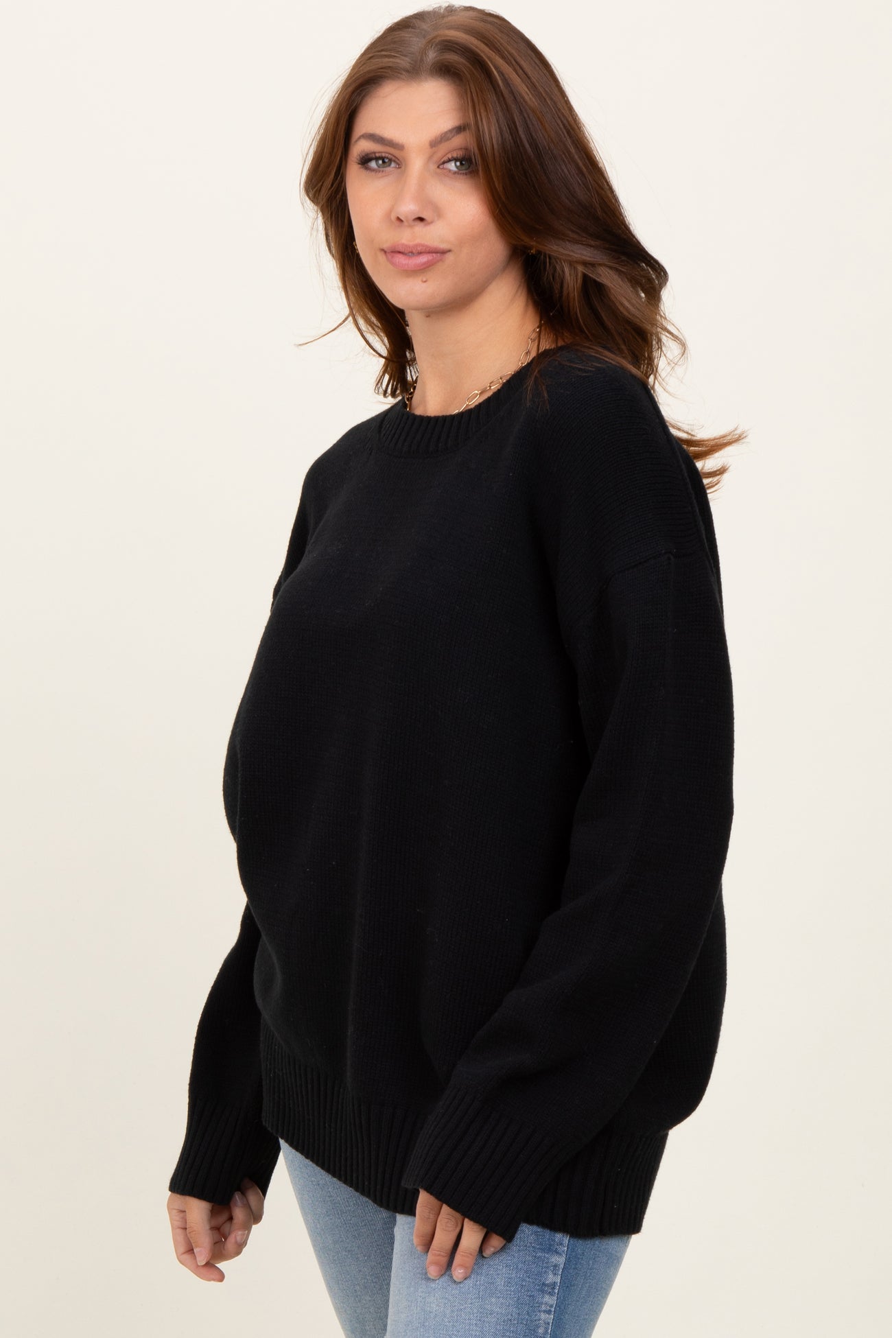 woman wearing a black oversized sweater with long sleeves and ribbed hem, styled with light blue jeans