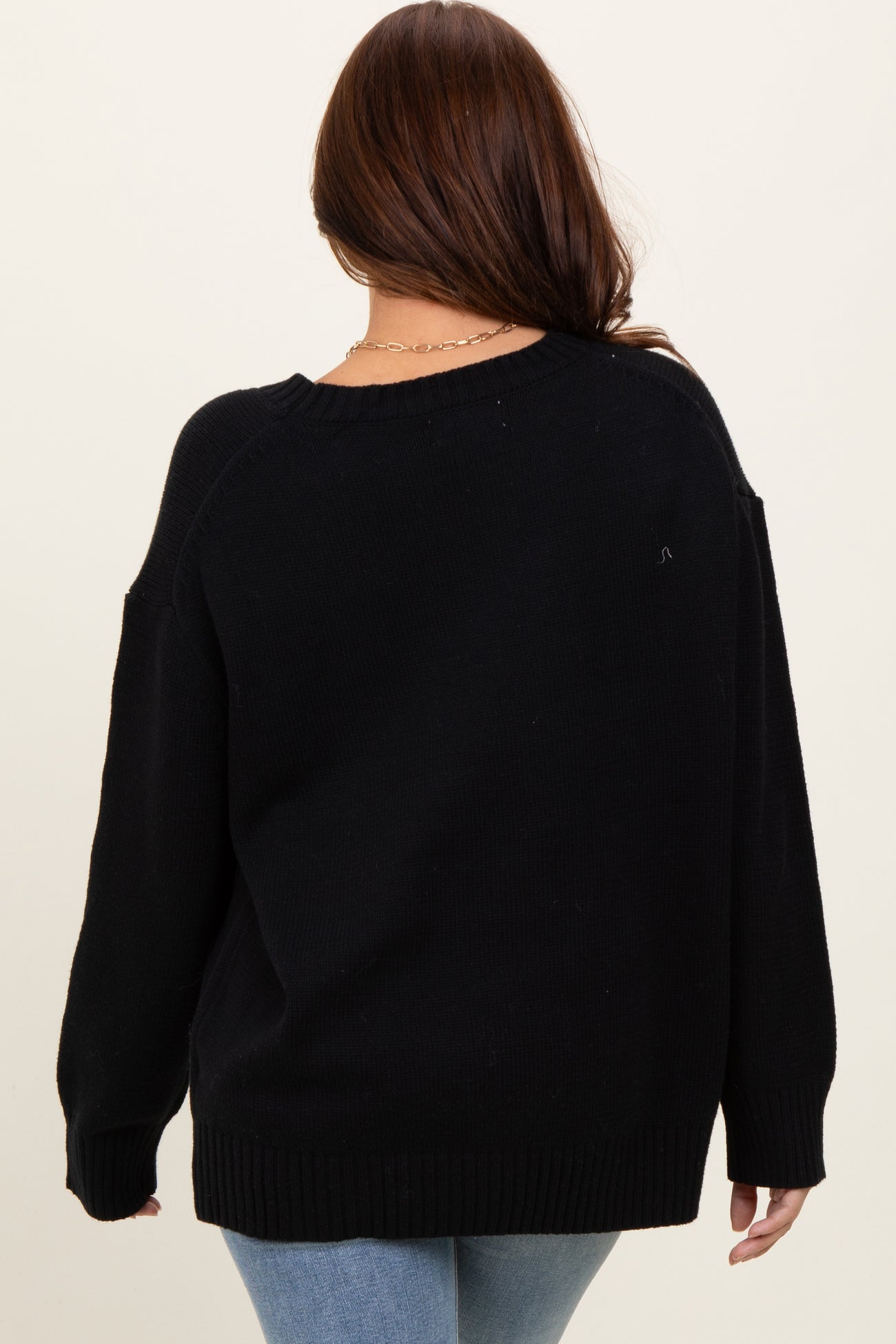 woman wearing a black oversized sweater from the back with long sleeves and a relaxed fit