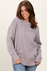 woman wearing a light purple oversized knit sweater and blue jeans, smiling at the camera