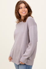 woman wearing a light purple oversized sweater with a relaxed fit and ribbed hem, standing and smiling