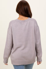 woman wearing a light gray oversized sweater with a round neckline and ribbed cuffs, viewed from the back