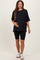 woman wearing a black oversized maternity t-shirt and black biker shorts, holding her baby bump