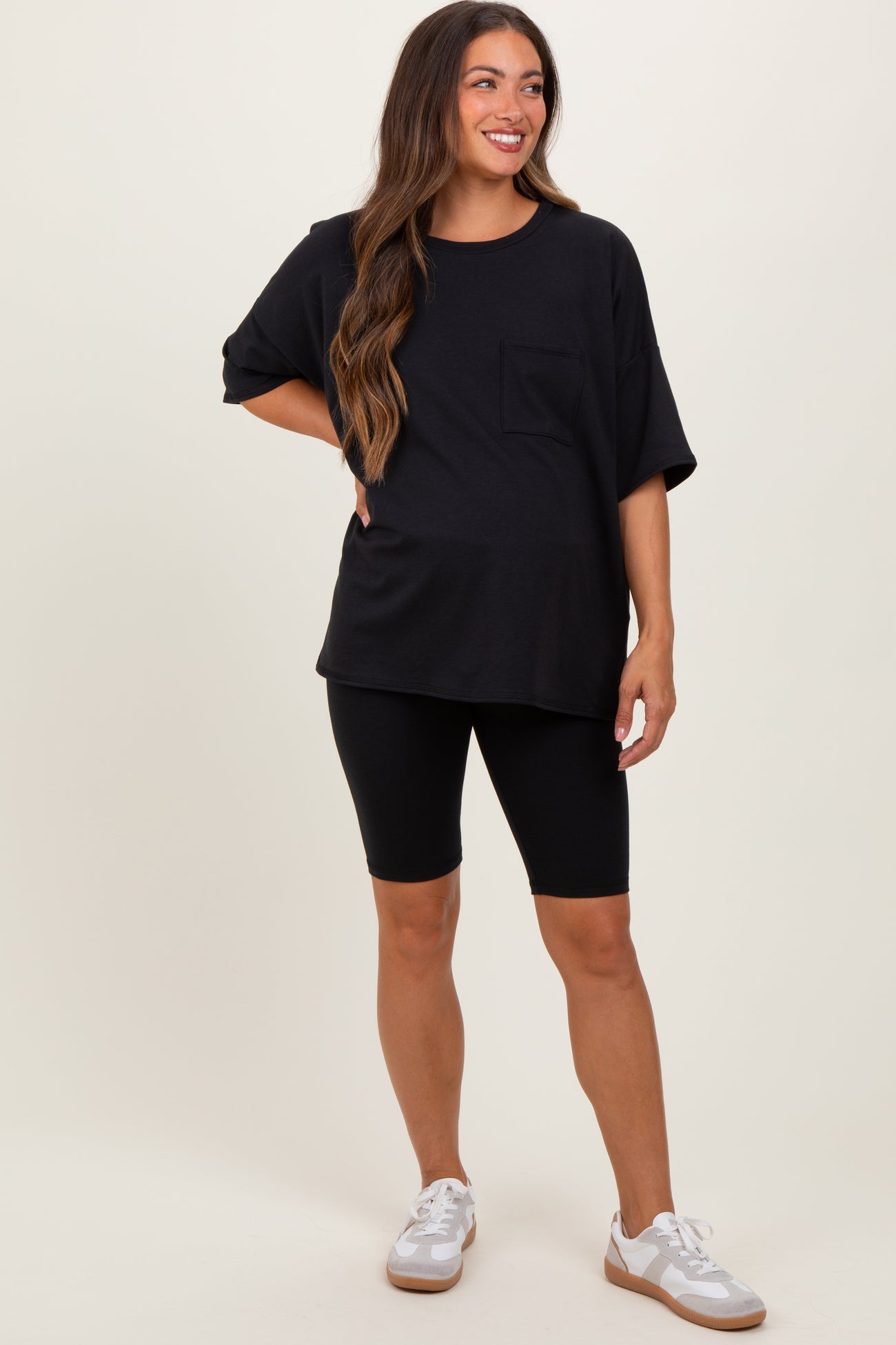 woman wearing a black oversized maternity top with a pocket and black maternity bike shorts