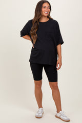 woman wearing a black oversized maternity top with a pocket and black maternity bike shorts