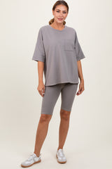woman wearing a gray oversized t-shirt with a pocket and gray bike shorts, posing with one hand on her hip