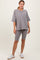 woman wearing a gray oversized t-shirt with a pocket and gray bike shorts, posing with one hand on her hip