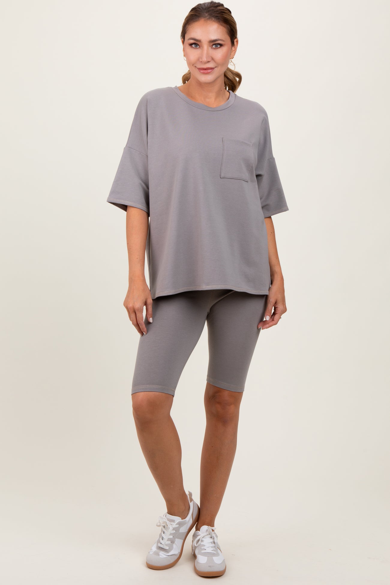 woman wearing a loose-fitting grey short sleeve t-shirt with a pocket and matching grey biker shorts