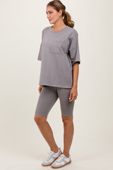 woman wearing a gray oversized t-shirt with pocket and matching gray bike shorts, standing in a relaxed pose