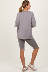 woman wearing a gray oversized sweatshirt and matching bike shorts, standing in a relaxed pose