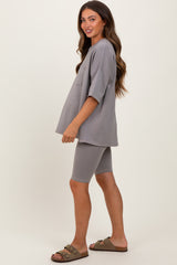 woman wearing a gray oversized maternity top with pockets and gray bike shorts, styled casually with sandals