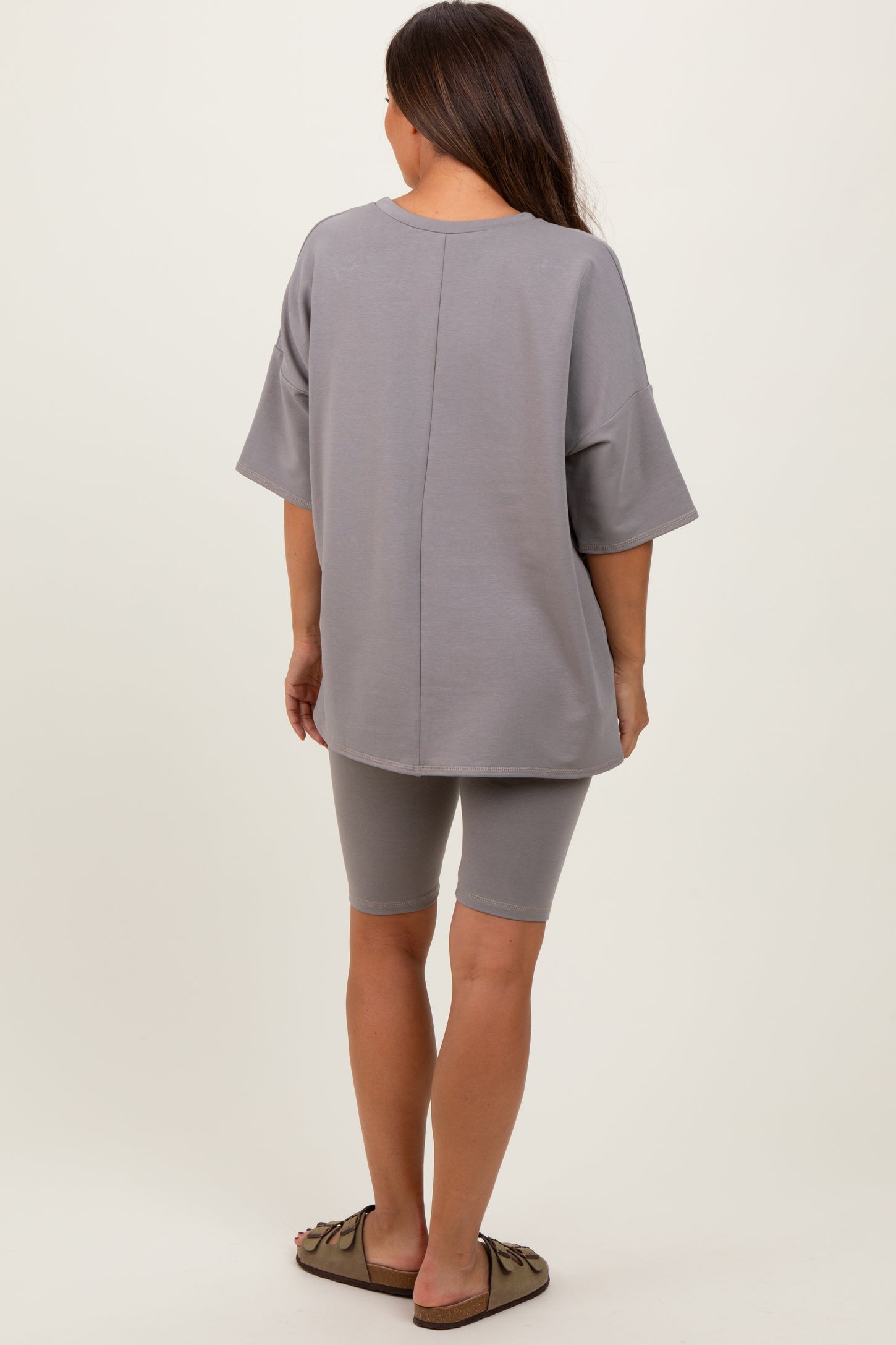 woman wearing a gray oversized maternity t-shirt and matching bike shorts, showing a relaxed fit from the back