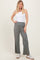 woman wearing a white ribbed tank top and sage green wide-leg pants, standing with one hand on her hip