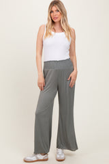 woman wearing an olive green pair of wide-leg pants with a smocked waistband and a white tank top