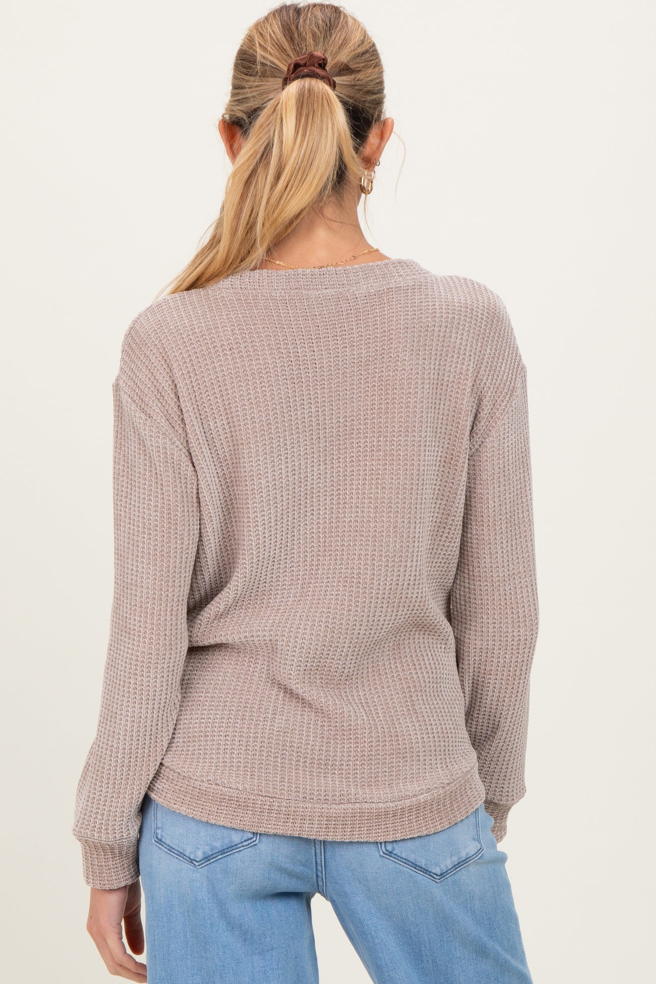 woman wearing a light brown maternity sweater with a relaxed fit and long sleeves, shown from the back