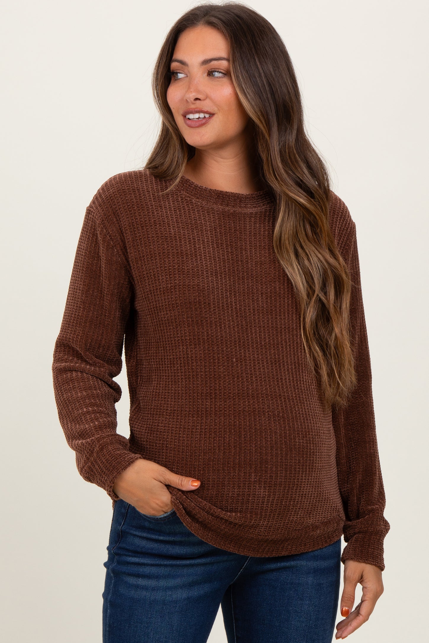 woman wearing a brown waffle knit maternity sweater and jeans, showing her baby bump