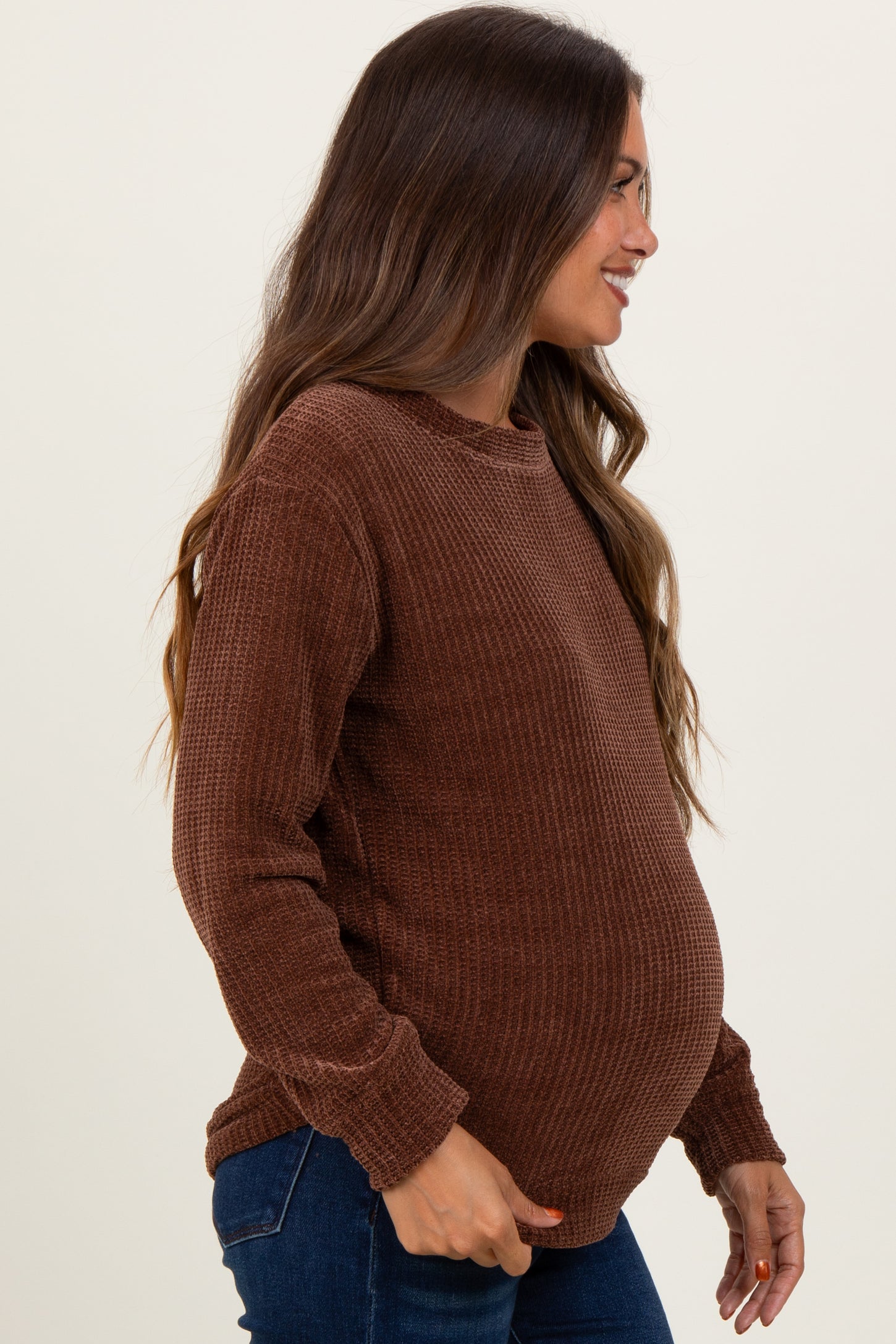 woman wearing a brown ribbed maternity sweater and showing her baby bump
