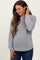 woman wearing a light gray maternity waffle knit long sleeve top, smiling and holding her baby bump