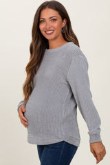 woman wearing a gray waffle knit maternity sweater and showing her baby bump