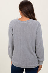 woman wearing a gray long sleeve maternity waffle knit top, showing the back view and styled with blue jeans