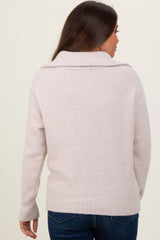 woman wearing a light pink maternity sweater with a ribbed collar and back detail, viewed from the back