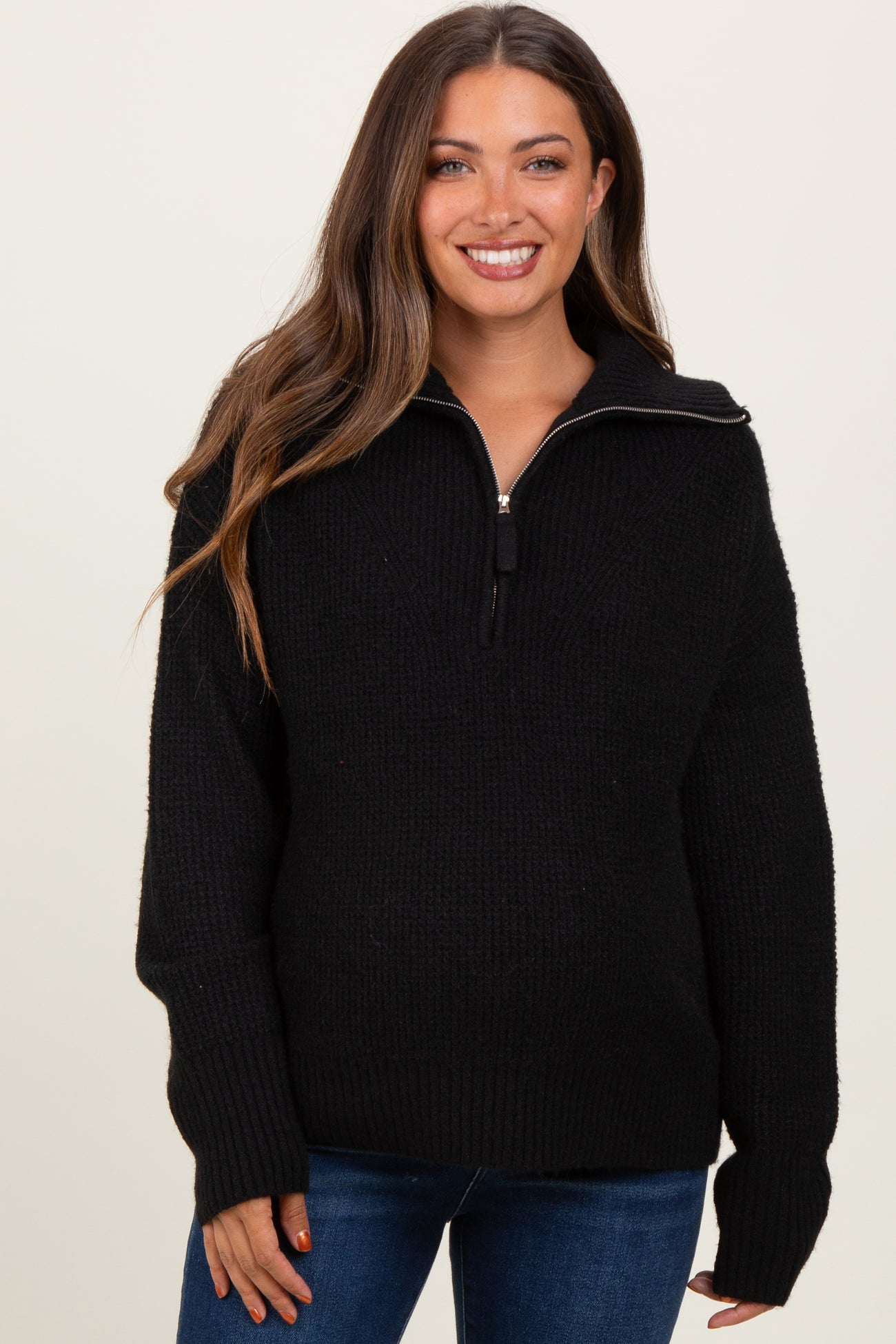 woman wearing a black maternity zip-up sweater with a relaxed fit and long sleeves, slightly showing her baby bump