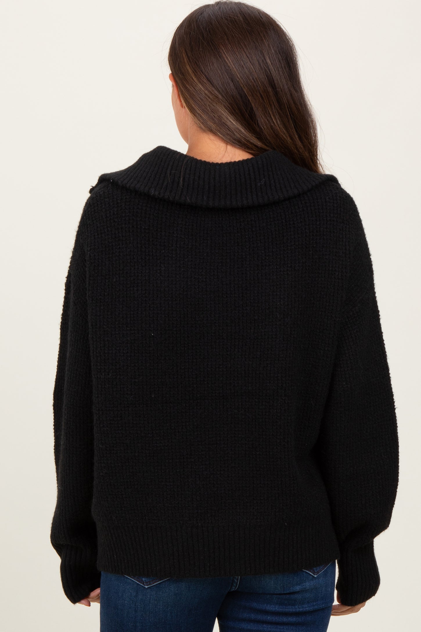 woman wearing a black oversized maternity sweater with a wide collar viewed from the back