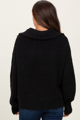 woman wearing a black oversized maternity sweater with a wide collar viewed from the back