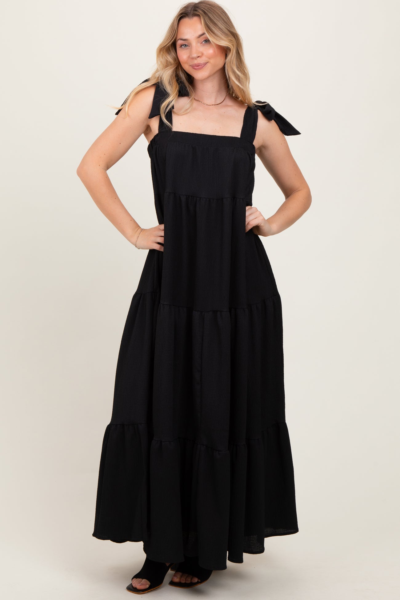 woman wearing a black tiered maxi dress with tie straps and a flowing silhouette