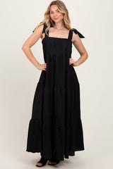 woman wearing a black tiered maxi dress with tie straps and a flowing silhouette