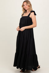 woman wearing a black tiered maxi dress with bow straps and a flowy silhouette