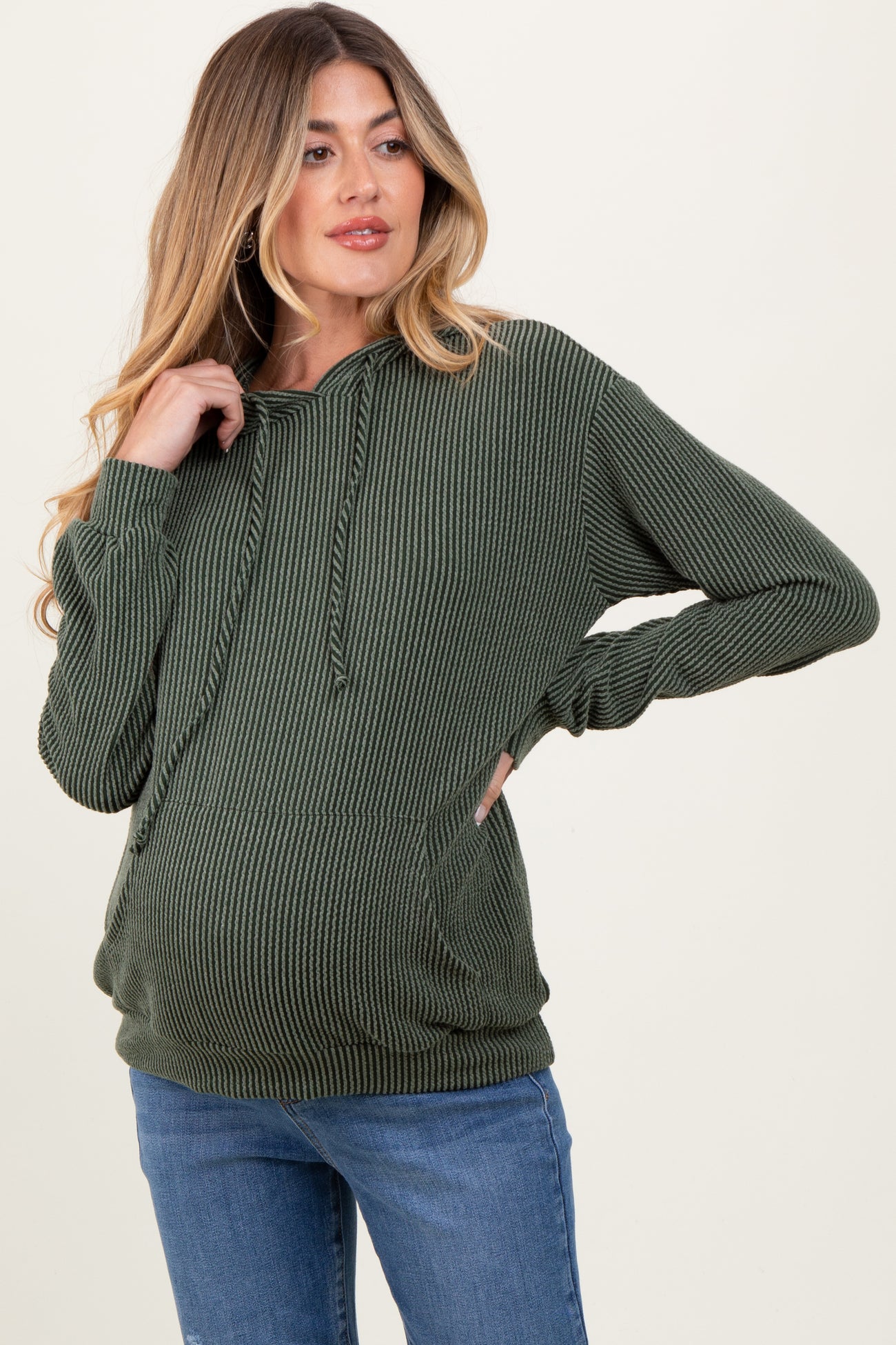 woman wearing a dark green ribbed maternity hoodie with a front pocket and a visible baby bump