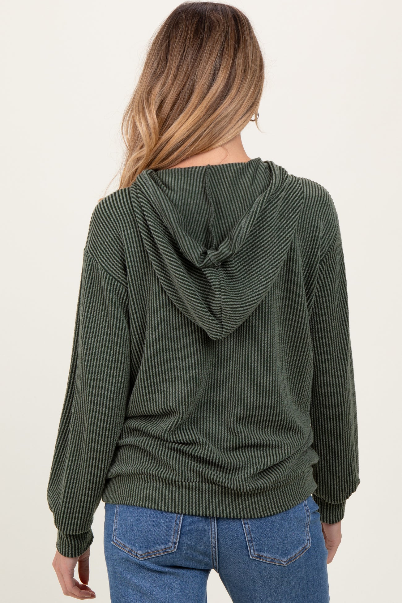 woman wearing a dark green striped maternity hoodie with a hood, viewed from the back