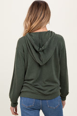 woman wearing a dark green striped maternity hoodie with a hood, viewed from the back