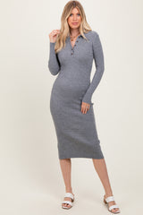 woman wearing a grey ribbed midi dress with long sleeves and button details, standing in strappy white sandals