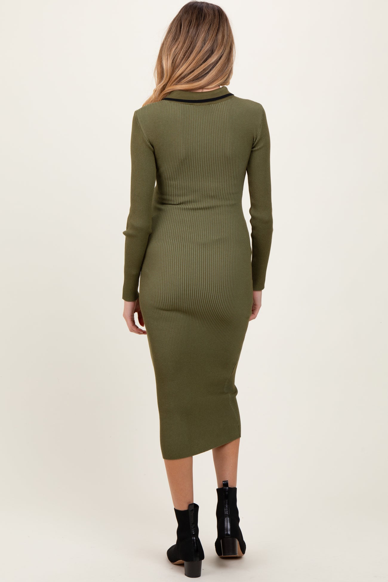 woman wearing an olive green ribbed long sleeve maternity dress, visible baby bump, back view