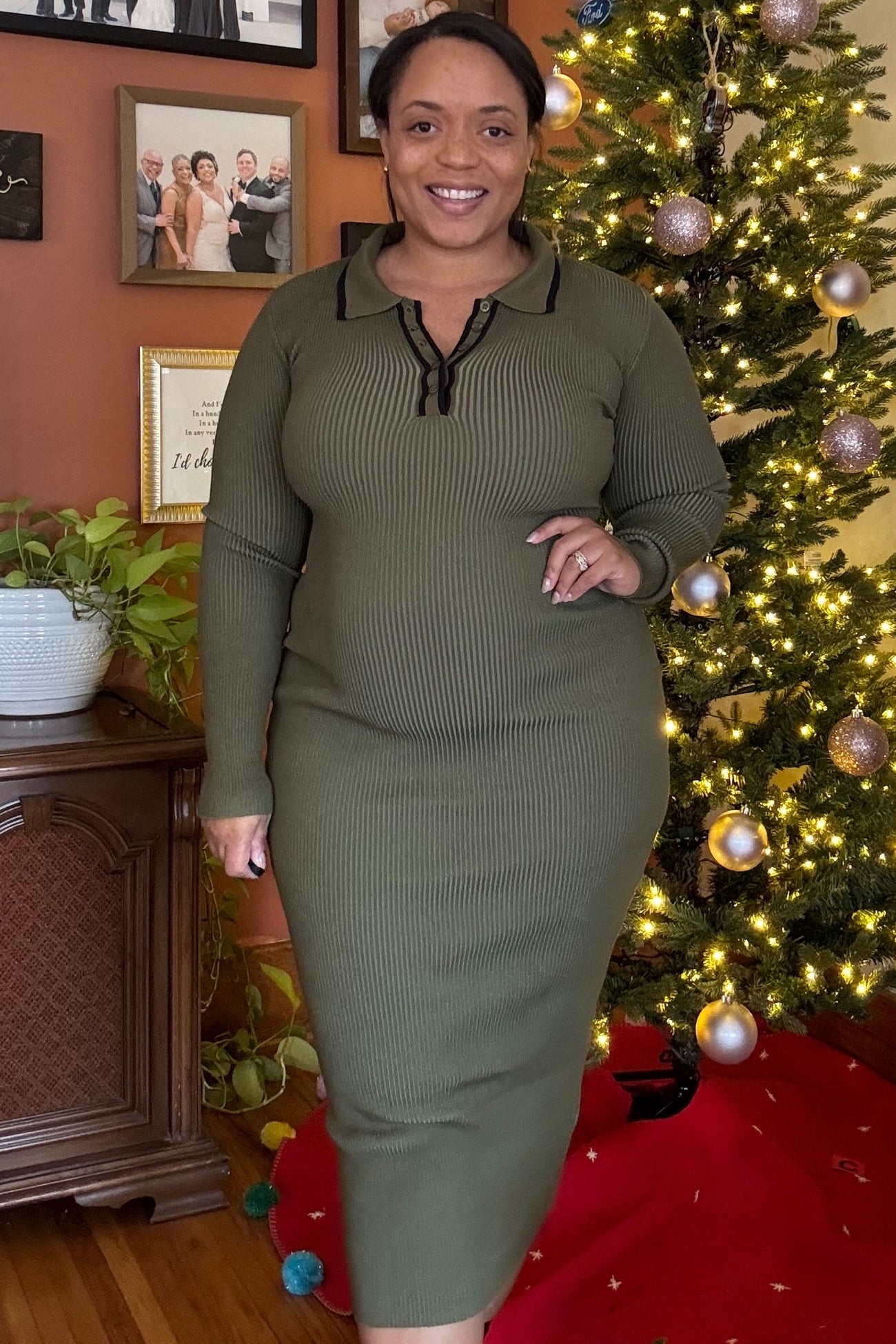 woman wearing a dark green maternity ribbed dress with a collar and zipper detail, showcasing her baby bump
