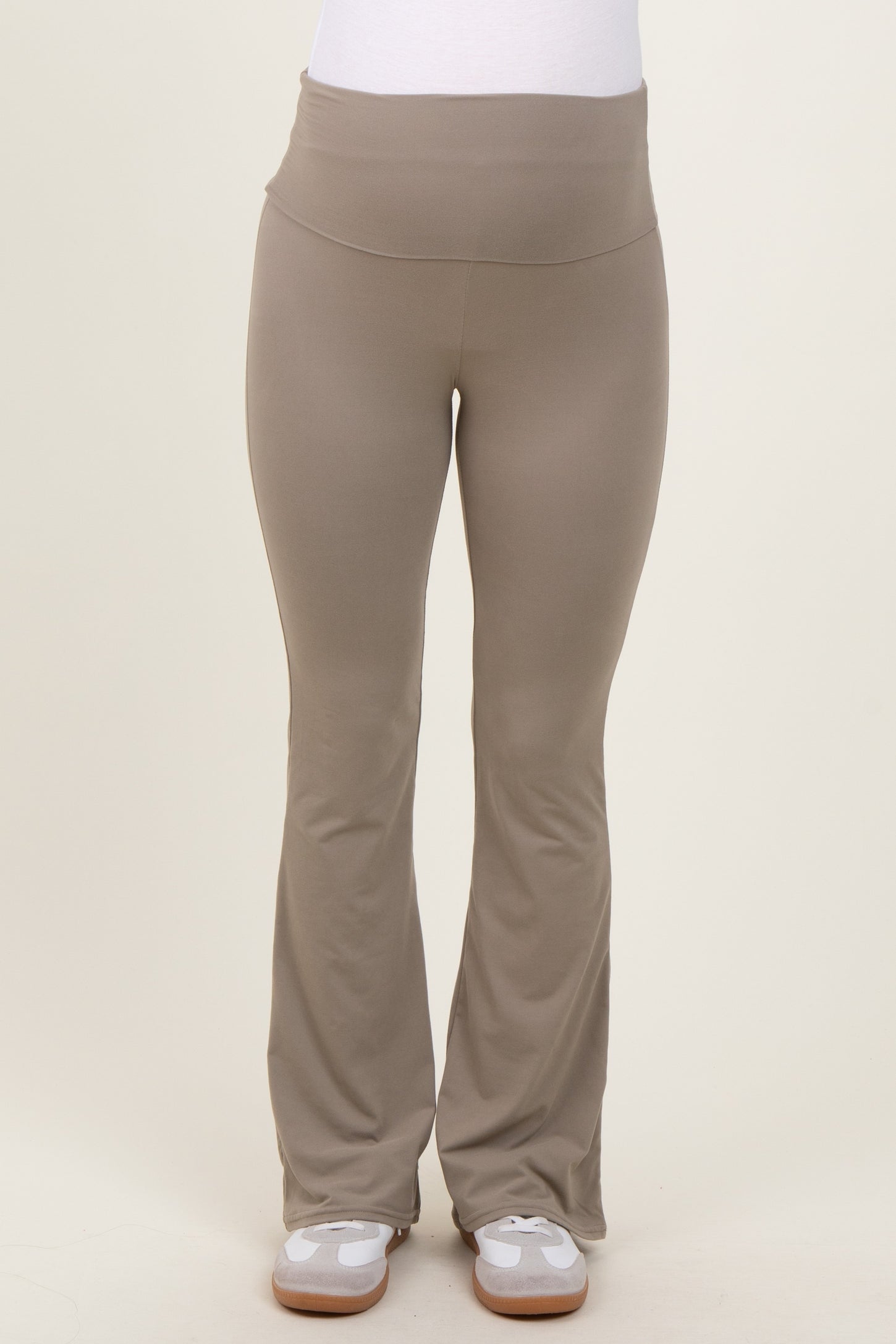 maternity wear in light taupe flared yoga pants with a wide waistband. model wearing the pants standing straight.